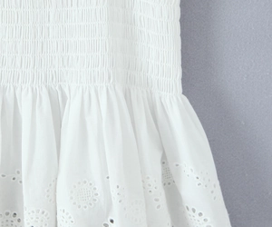 Détail macro du tissu en coton blanc avec smocks élastiques et dentelle brodée ajourée