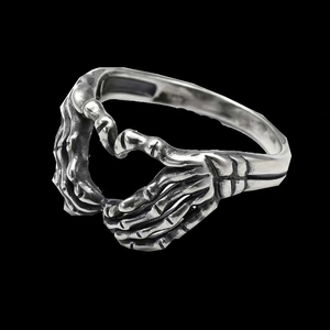 Macro detail of vintage heart skull hand ring with antique silver finish and bone textures