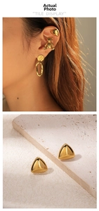 Detail view of polished golden geometric triangle stud earrings with shiny metallic finish