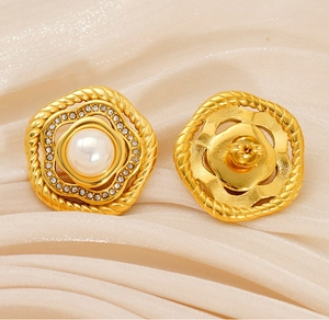 Dettaglio di orecchini vintage in oro con perle e strass su sfondo di seta