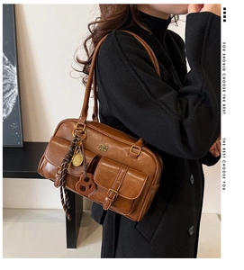 Side view of brown vintage PU leather hobo bag with buckled pockets and metal charms