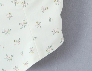 Detailopname van chiffonstof met roze en gele bloemenprint op een witte basis