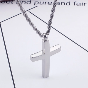 Gros plan d'un pendentif croix en acier titane argenté avec une chaîne torsadée détaillée