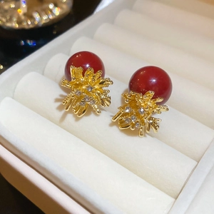 Detailed close-up of red pearl earrings with golden firework cluster and inlaid crystals