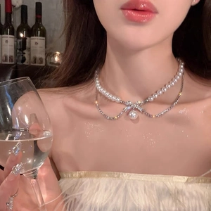 Double-layered pearl necklace with rhinestone bow pendant shown on a model