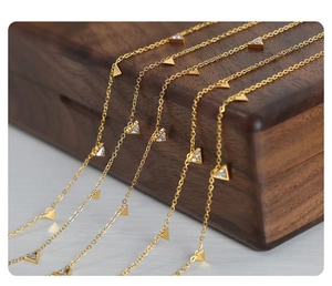 Detailed macro view of layered gold titanium necklaces with triangle crystal pendants