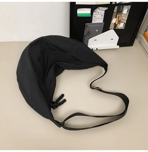 Détail du sac en nylon noir avec bandoulière réglable et tirette de zip nouée