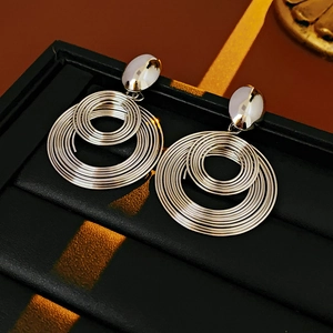 Macro detail of silver coiled round metal earrings on a black textured jewelry box