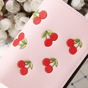 Close-up of pink litchi grain leather wallet with red cherry embroidery detail