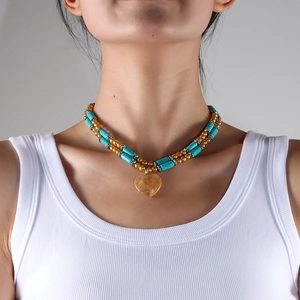 Boho turquoise and gold beaded double layer necklace with a heart stone pendant on a model