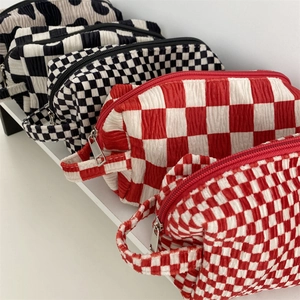 Detailed view of velvet cosmetic bags in checkered and cow patterns with metal zipper