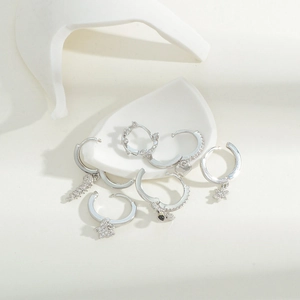 Set di orecchini in argento con ciondoli in zircone su sfondo di pietra minimalista