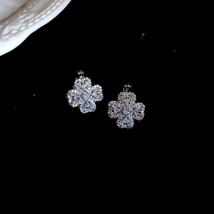 Gros plan sur des boucles d'oreilles trèfle en argent avec zircons étincelants