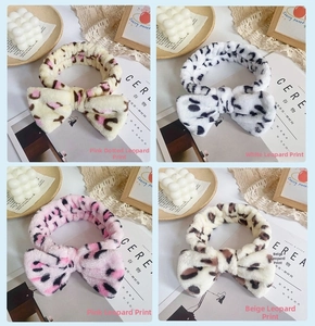 Detail of four leopard print coral fleece bow headbands in pink, white, and beige colors