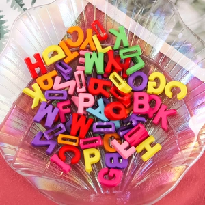 Macro detail of macaron colored acrylic alphabet beads in a shell shaped glass bowl