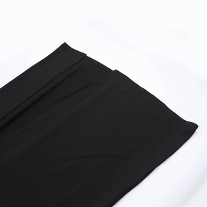 Detail of the split hem on a black bodycon dress with smooth knitted fabric texture