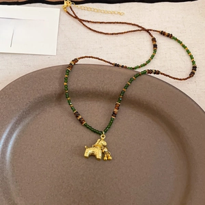 Detailed close-up of tiger eye beaded necklace with a golden puppy pendant on a ceramic tray