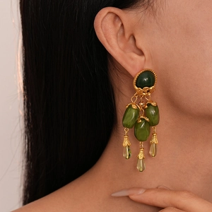 Boucles d'oreilles vintage en résine vert olive avec pampilles dorées sur mannequin