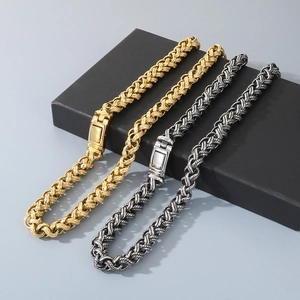 Detail of woven stainless steel chain bracelets in gold and dark silver finishes