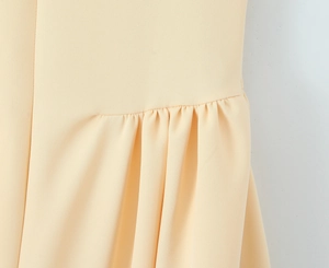 Gros plan détaillé sur les élégants plis à la taille de cette robe vintage beige clair