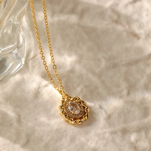 Macro shot of 18K gold plated oval pendant with zircon cluster and twisted rope edge