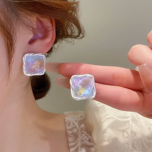 Close-up of square silver-rimmed earrings with purple marble resin and gold foil texture