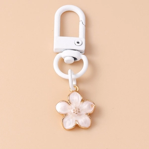 Detail of pink cherry blossom keychain with gold-plated edges and white D-ring clasp