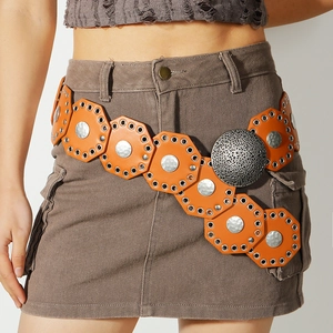 Detail of bohemian orange wide belt with metal discs and large hammered round buckle
