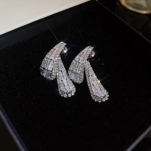 Macro shot of silver teardrop earrings with zircon stones in a black velvet box