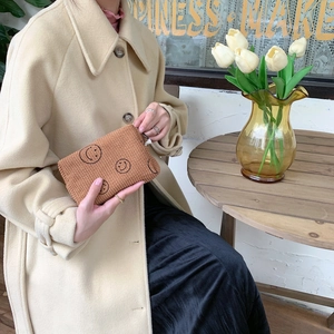 Brown corduroy cosmetic bag with black smiley faces shown in a cozy lifestyle setting