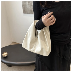 Close-up of ivory cloud bag featuring soft pleated texture and minimalist handle design