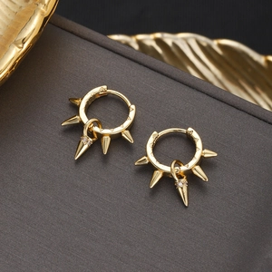Close-up of gold geometric spike hoop earring with micro zircon inlay on dark texture