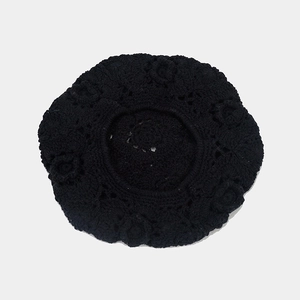 Detailed close-up of a black crochet hollow floral pattern on a cotton beret hat