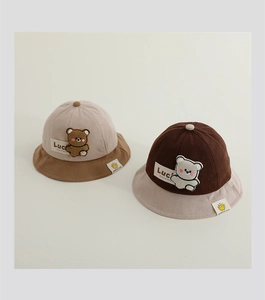 Detailed close-up of corduroy baby sun hat with cute bear patch and Luck label
