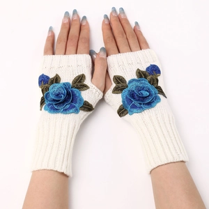 Detail of cream knit fingerless glove featuring blue 3D floral embroidery and warm texture