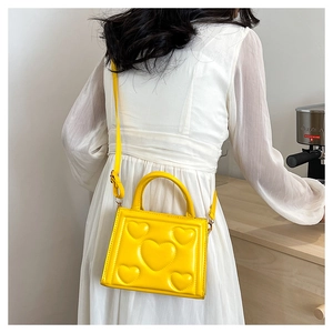 Détail du motif cœur en relief 3D sur le sac à main jaune en cuir PU pour femme