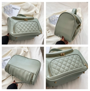 Green quilted cosmetic bag detail view, portable travel toiletry pouch with gold hardware.