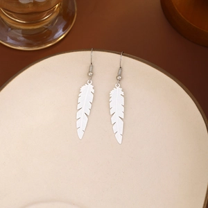 Detailed view of silver bohemian feather drop earrings on a ceramic dish edge