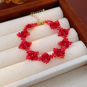 Detail view of red beaded flower bracelet with gold clasp and adjustable metal chain