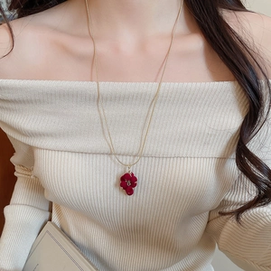Detailed close-up of a red flocked grape tassel necklace on a delicate gold chain