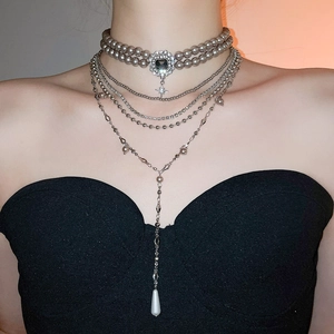 Macro view of multi-layered pearl choker necklace with vintage pendant and silver chains