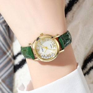 Detailed close-up of a ladies' quartz watch with gold case and green leather strap