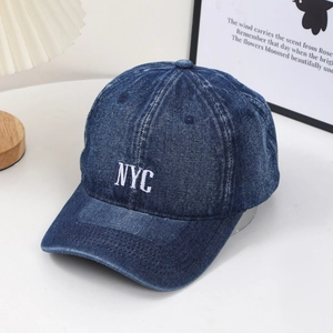 Deep blue washed denim baseball cap with white NYC embroidery in a minimalist setting