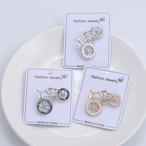 Detail view of bicycle brooches with rhinestones and pearls on display cards