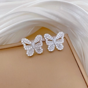 Close-up of silver butterfly earrings with sparkling cubic zirconia on white silk