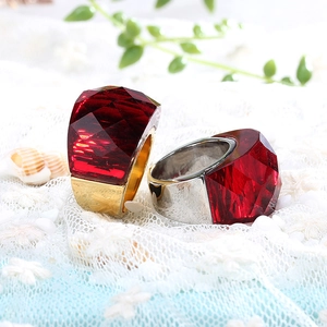 Detailed view of red faceted crystal rings in gold and silver plating on white lace