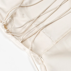 Dettaglio dell'abito in raso beige con sottili spalline incrociate e zip invisibile