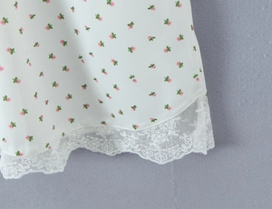 Gros plan sur la robe en satin blanc avec motif floral rose et bordure en dentelle fine