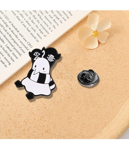 Detail of Punpun enamel pin with scarf on book background and floral decor