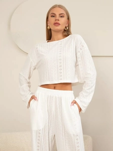 Détail de la broderie anglaise blanche sur le haut à manches longues et le pantalon